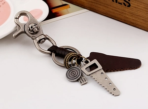 Detail of vintage leather keychain with alloy saw charm and skull hook on wooden background