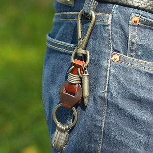 Vintage brown leather keychain with bullet charm on blue jeans loop in outdoor setting
