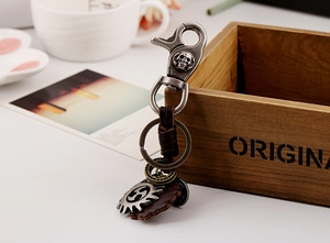 Close-up of retro punk keychain with skull buckle, woven leather and gear charms
