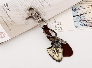 Detail of vintage leather keychain with bronze shield pendant and punk skull ring