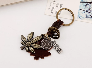 Macro detail of bronze leaf charm and brown leather pendant on retro punk keychain