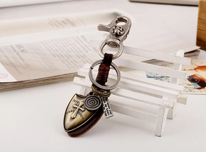 Detail of vintage punk leather keychain with skull hook and bronze cross shield pendant