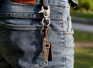 Detail of vintage leather braided keychain with saw pendant clipped to denim jeans loop