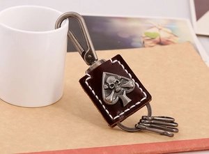 Close-up of retro punk leather keychain with skull spade metal emblem and white stitching