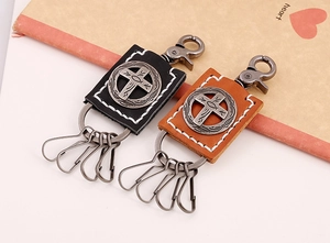 Close-up of vintage leather keychains in black and brown with metal cross emblems