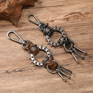 Punk style leather keychain with metal spikes and vintage alloy hooks on wooden background