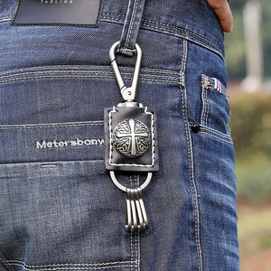 Retro punk cowhide leather keychain with metal cross emblem on blue denim jeans