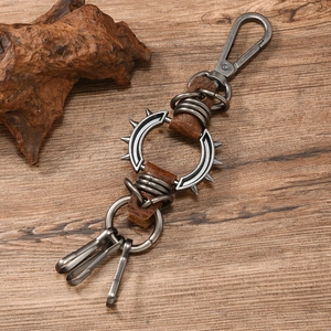 Detail of punk leather keychain with metal spikes and hooks on a rustic wooden background