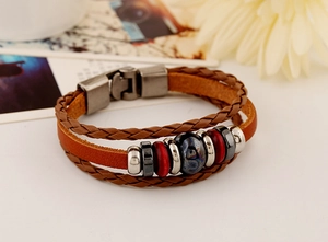 Macro detail of multilayer braided leather bracelet with vintage metal clasp and beads