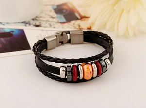 Detail of multi-layer leather bracelet with orange marble bead and braided cords