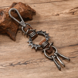 Close-up of punk leather keychain with spikes and vintage bronze hardware on wood