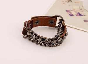 Macro view of vintage punk leather bracelet featuring skull charms and metal chain link