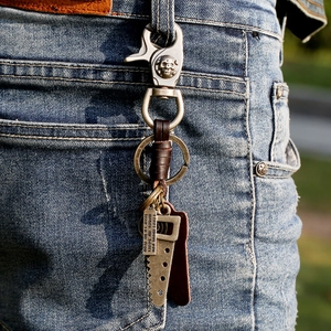 Vintage leather keychain with saw pendant and skull hook on denim jeans