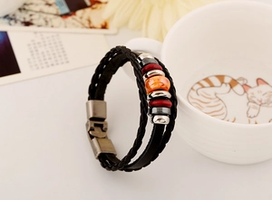 Detail of multilayer braided leather bracelet with orange beads and vintage metal clasp