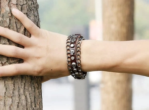 Detailed view of punk leather bracelet featuring silver skull relief and metallic studs