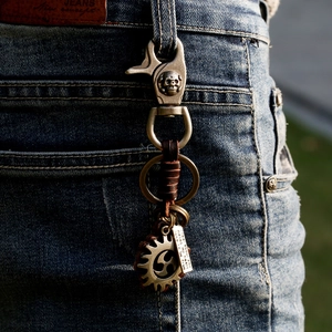Vintage punk leather keychain with skull hook and gear charms on denim jeans