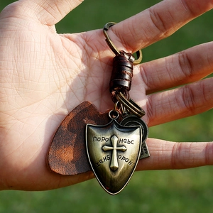 Retro punk woven leather keychain featuring a bronze shield cross charm held by hand