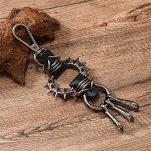 Close-up of punk leather keychain with metal spikes and hooks on a wood surface