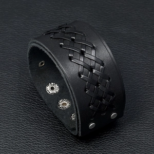 Macro detail of men's punk wide black leather bracelet featuring intricate cross weaving