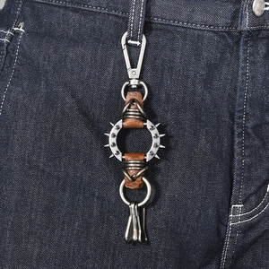 Punk style leather keychain with metal spikes and snap hook on blue jeans
