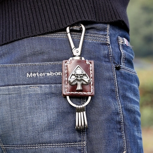 Retro punk style leather keychain with metal skull and spade charms on denim