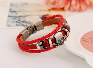 Détail d'un bracelet punk en cuir tressé rouge avec pendentif tête de mort argenté