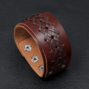 Close-up of wide vintage brown leather bracelet with braided texture and snap buttons