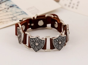 Detail of vintage punk leather bracelet with silver shield charms and metal buckles