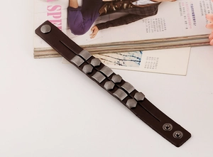 Detail of dark brown leather punk bracelet with antique silver geometric metal studs