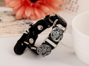 Detail of vintage black leather punk bracelet with engraved silver floral metal studs