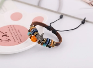 Detalle de pulsera vintage de cuero con cuentas, colgante de hoja de arce y cordón ajustable
