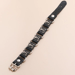 Close-up of punk leather bracelet with silver skull charms and metal link connectors