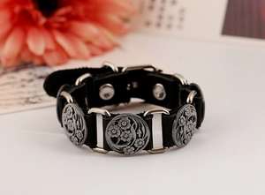 Detail of a vintage black leather bracelet with silver floral engravings and a buckle strap