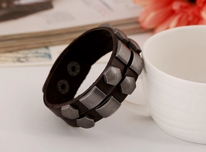 Close-up of brown leather punk bracelet featuring vintage silver rivets and snap button closure