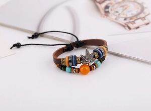 Detalle de pulsera de cuero multicapa con cuentas y colgante de hoja de cáñamo plateado