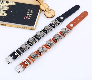Detail of punk leather bracelets with metal skulls in black and brown finishes