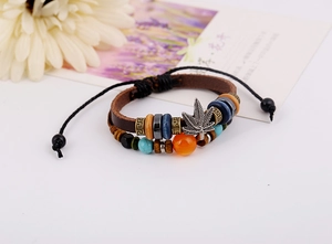 Vista macro de la pulsera multicapa de cuero vintage con cuentas y colgante de hoja de plata