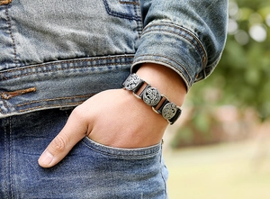 Detail of punk leather bracelet showing carved silver-tone metal studs on a man's wrist