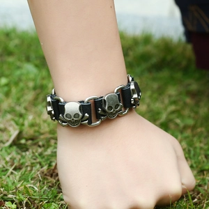 Detail of punk leather bracelet featuring vintage metal skulls and silver ring connectors