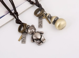Detail of vintage bronze bear and gourd pendants with brown braided leather cord necklaces