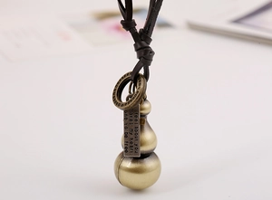 Macro shot of vintage bronze gourd pendant with engraved tag on brown leather cord