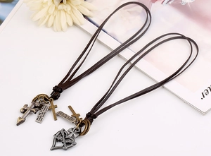 Macro detail of dark brown leather necklaces with vintage silver heart and cross pendants