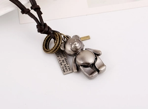 Detailed close-up of retro teddy bear pendant and engraved plate on a leather necklace