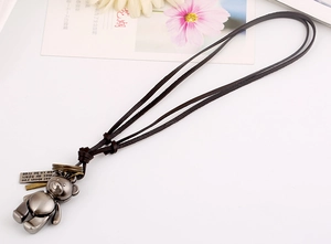Detailed view of long leather cord necklace with vintage silver articulated bear pendant