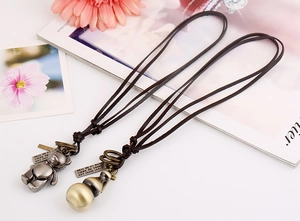 Detailed view of vintage alloy bear and gourd charms on long leather necklaces