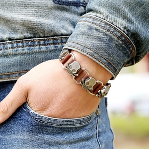 Men's punk skull bracelet made of brown leather and vintage silver metal on denim background