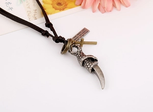 Macro detail of punk leather necklace with dragon claw, cross, and engraved plate charms