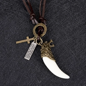 Gros plan d'un pendentif dent de loup vintage avec croix en bronze sur cordon en cuir