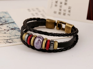 Macro shot of multi-layer leather bracelet with purple ceramic bead and bronze clasp