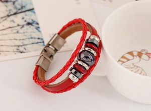 Dettaglio del bracciale multistrato in pelle rossa con perline punk e chiusura magnetica